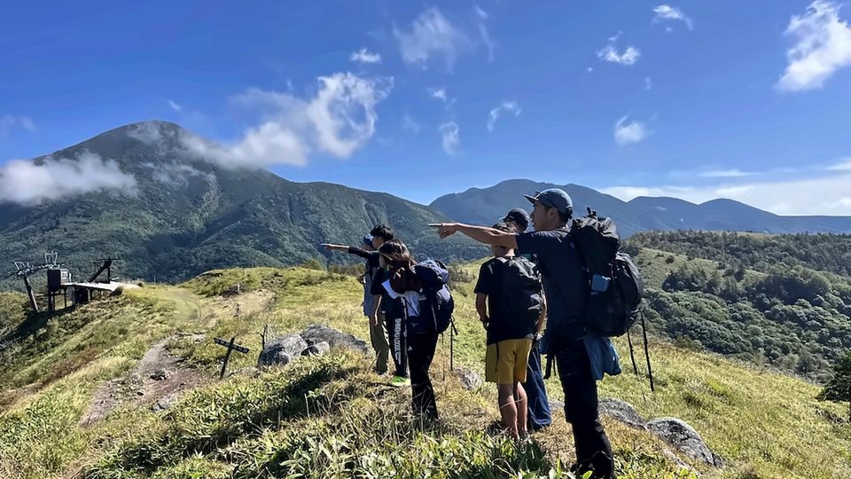Guide pointing out peaks to hikers on the Kirigamine grasslands